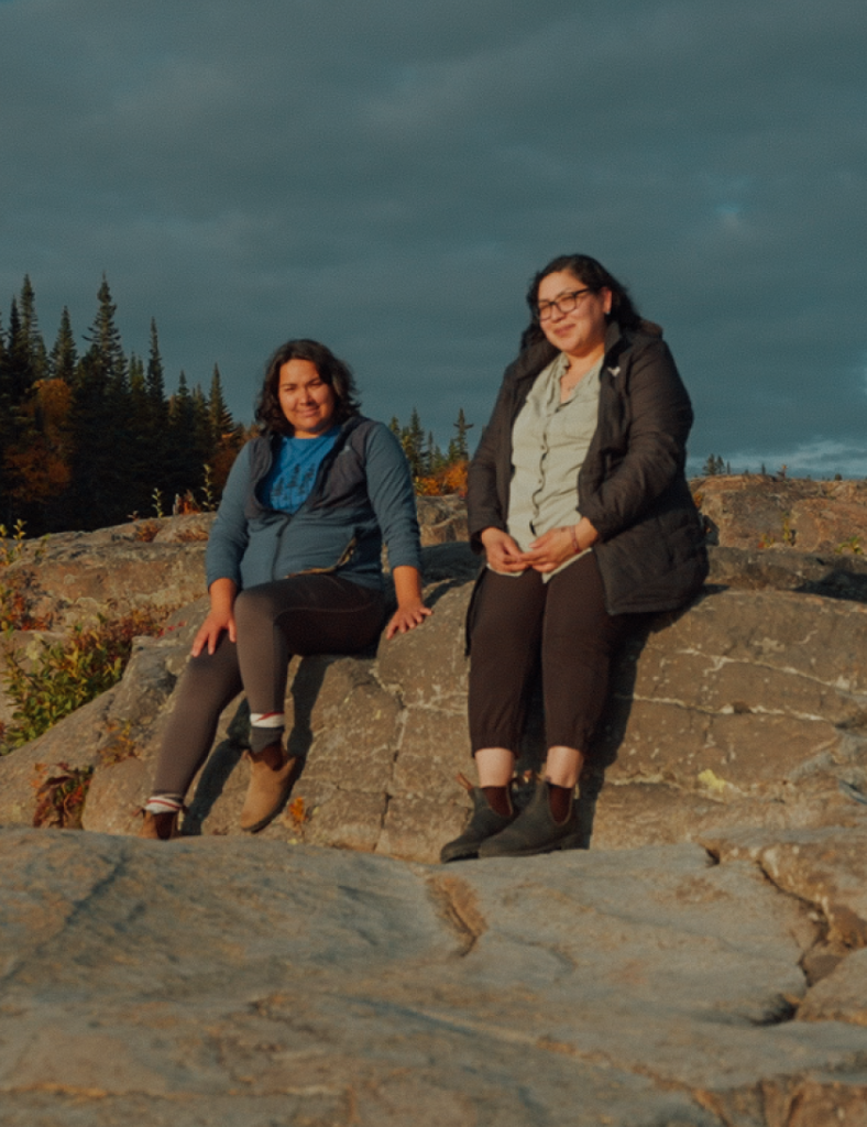 Uapukun Mestokosho and Shanice Mollen Picard sitting on rocks.